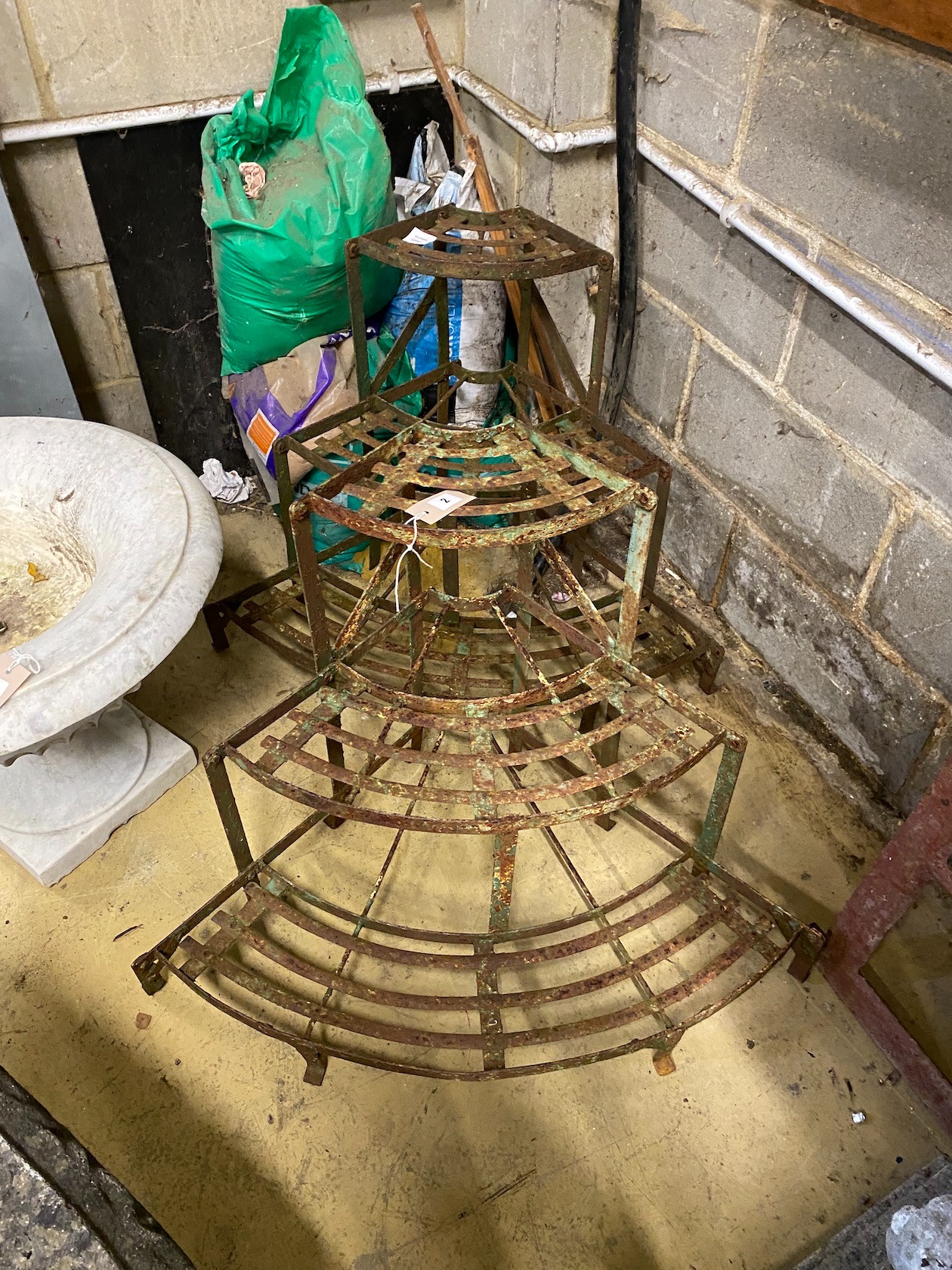 A pair of slatted wrought iron bowfronted three tier plant stands, larger width 82cm, height 63cm